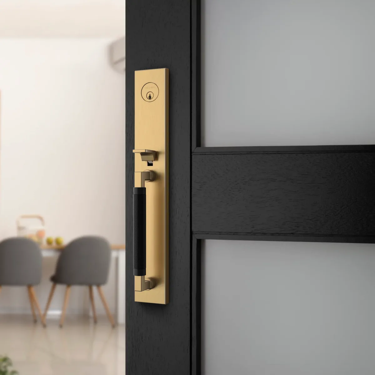 Gramercy knurled handleset mounted on a dark wood entry door, satin brass plate and black knurled pull