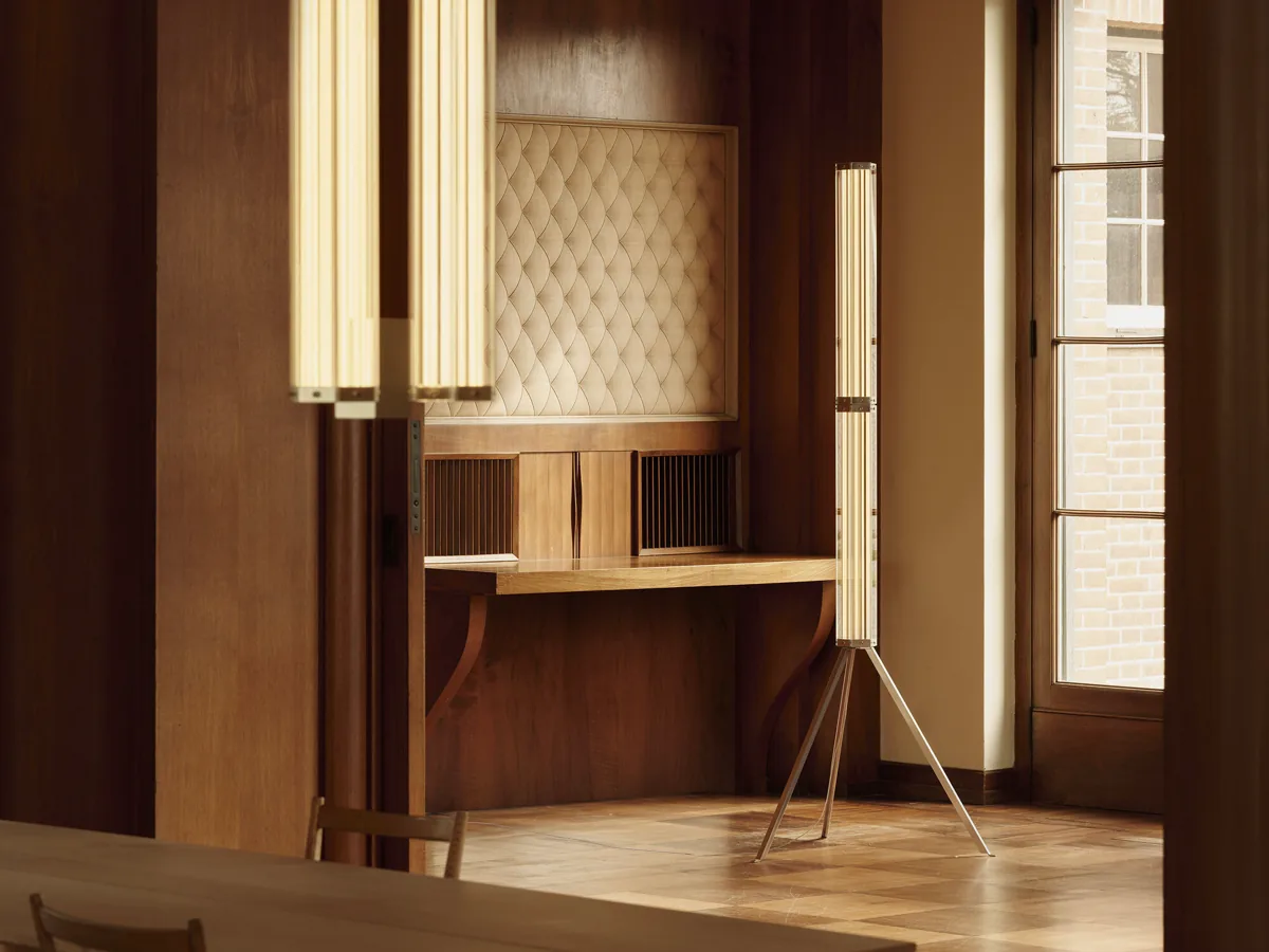 SuperWire F standing on parquet beside wood paneling, hexagonal glass column glowing 2700K